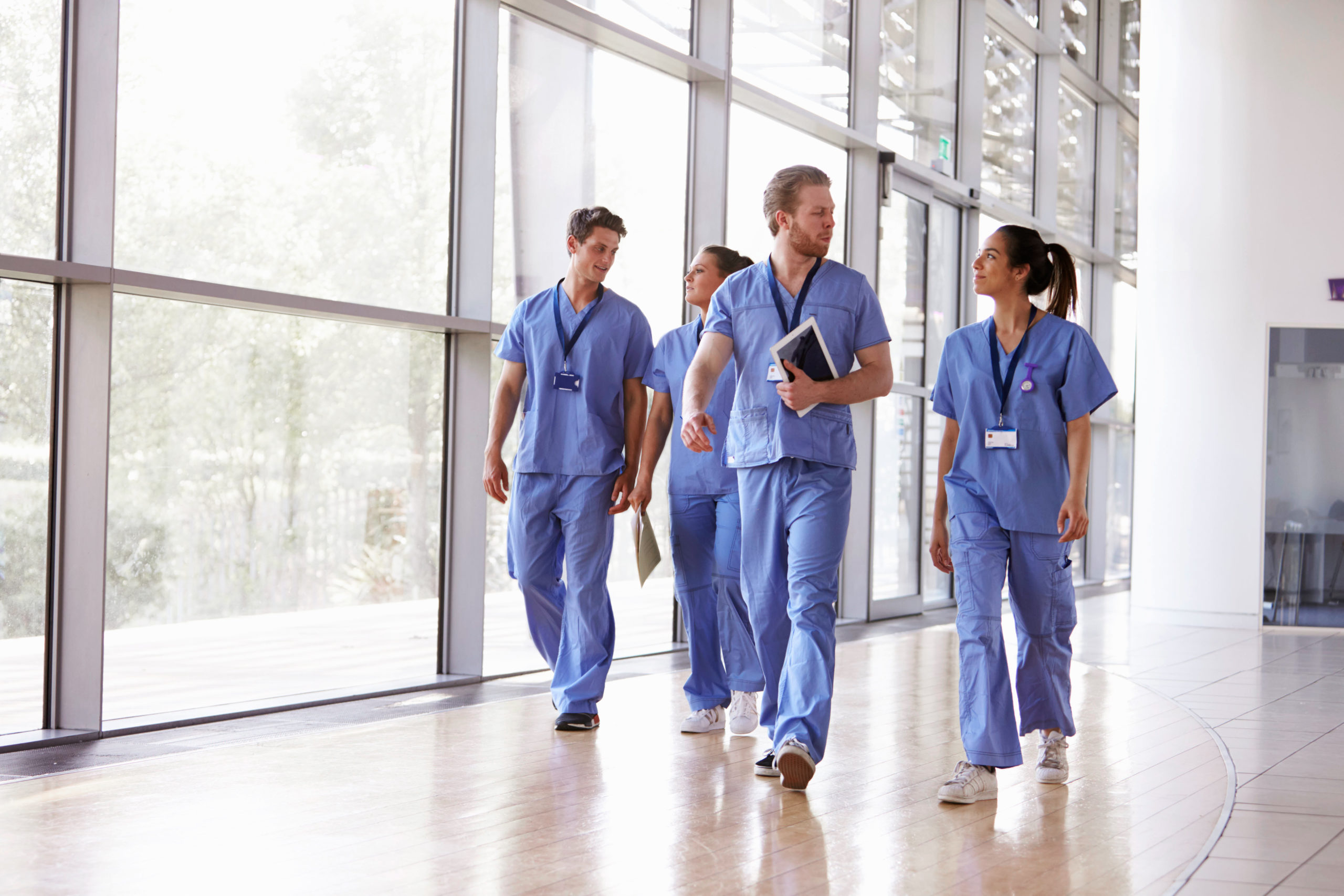 Four,healthcare,workers,in,scrubs,walking,in,corridor